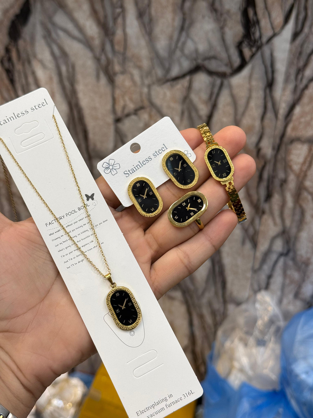 The image displays a matching set of gold-colored stainless steel jewelry